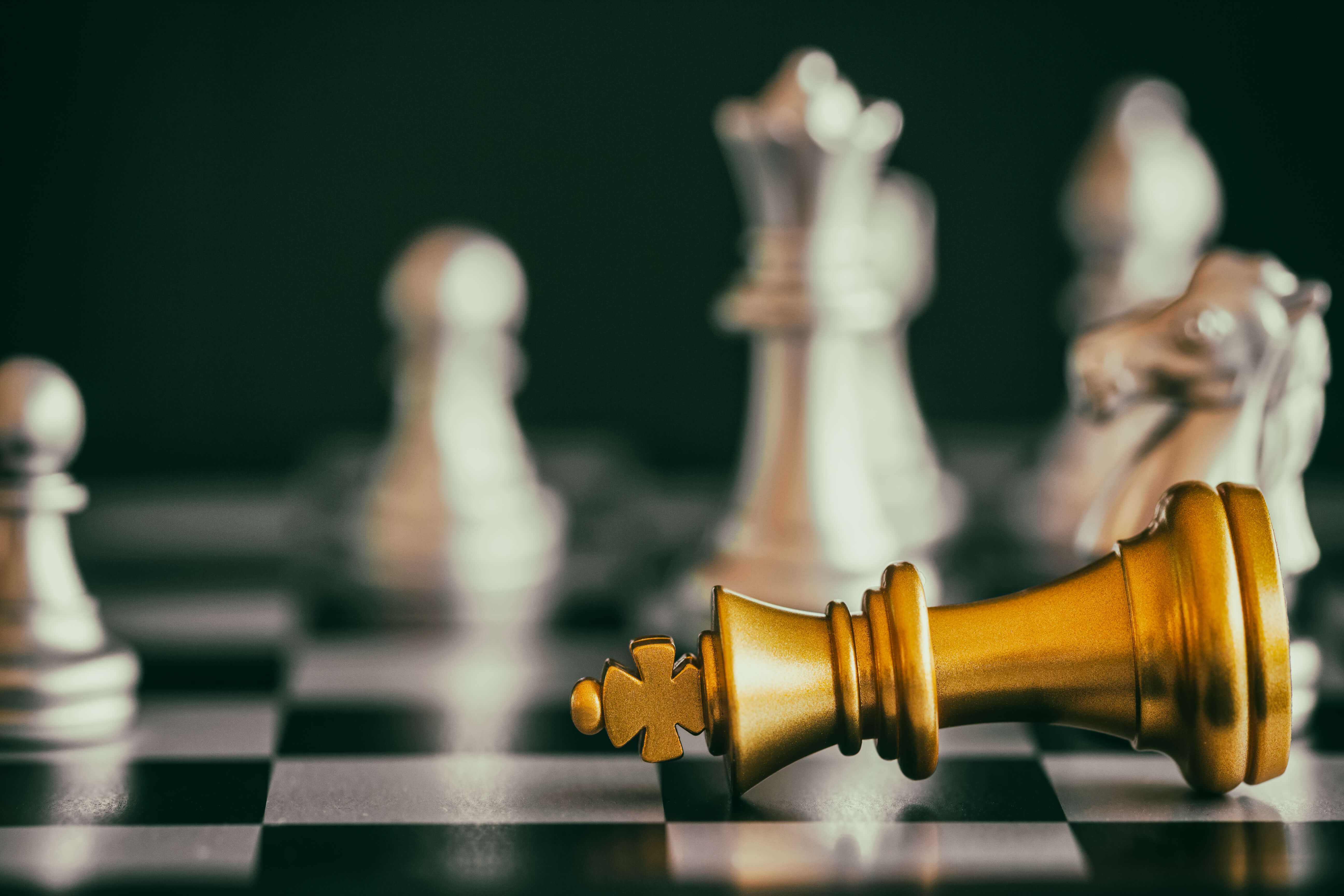 Chess king fallen on chessboard representing business competition, industrial strategy, and market risks