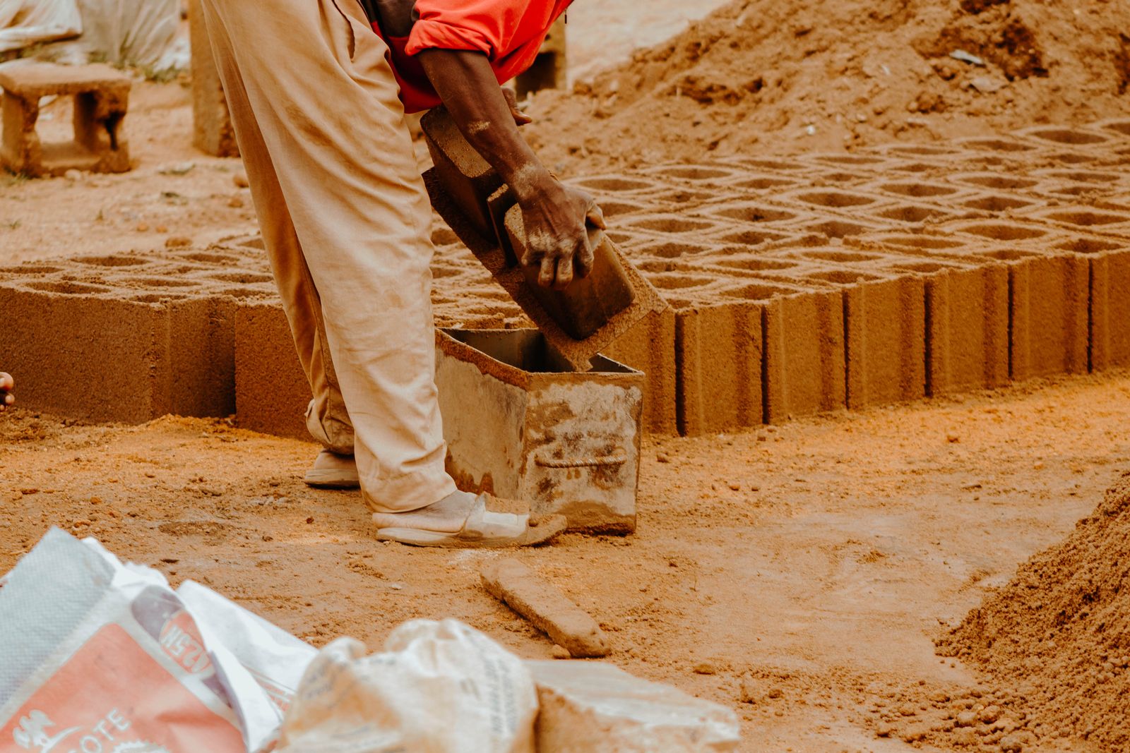 Worker moulding blocks by hand at an outdoor yard